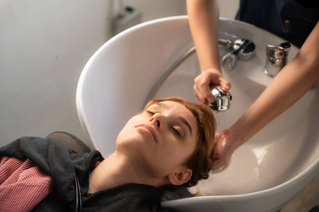 Woman having her hair washed in a salon, illustrating gentle scalp care for people with psoriasis
