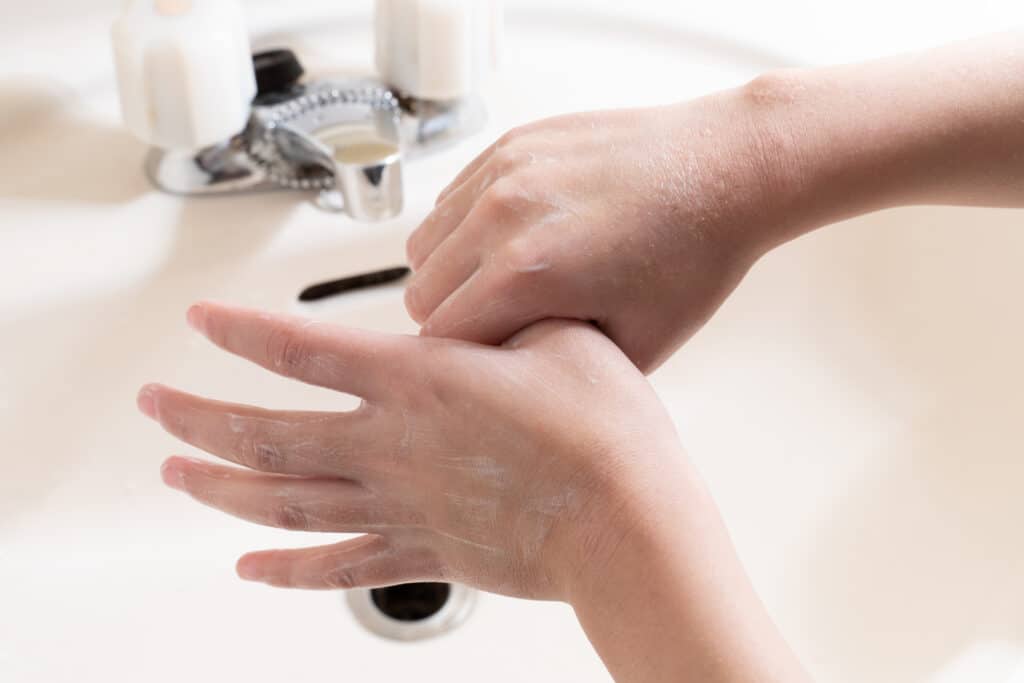 Child washing hands with soap under running water